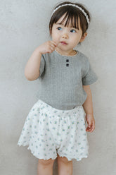 Toddler Girl Standing in Avauma Petit Bloom Blooming White Shorts, Summer Baby Shorts with Delicate Flower Pattern